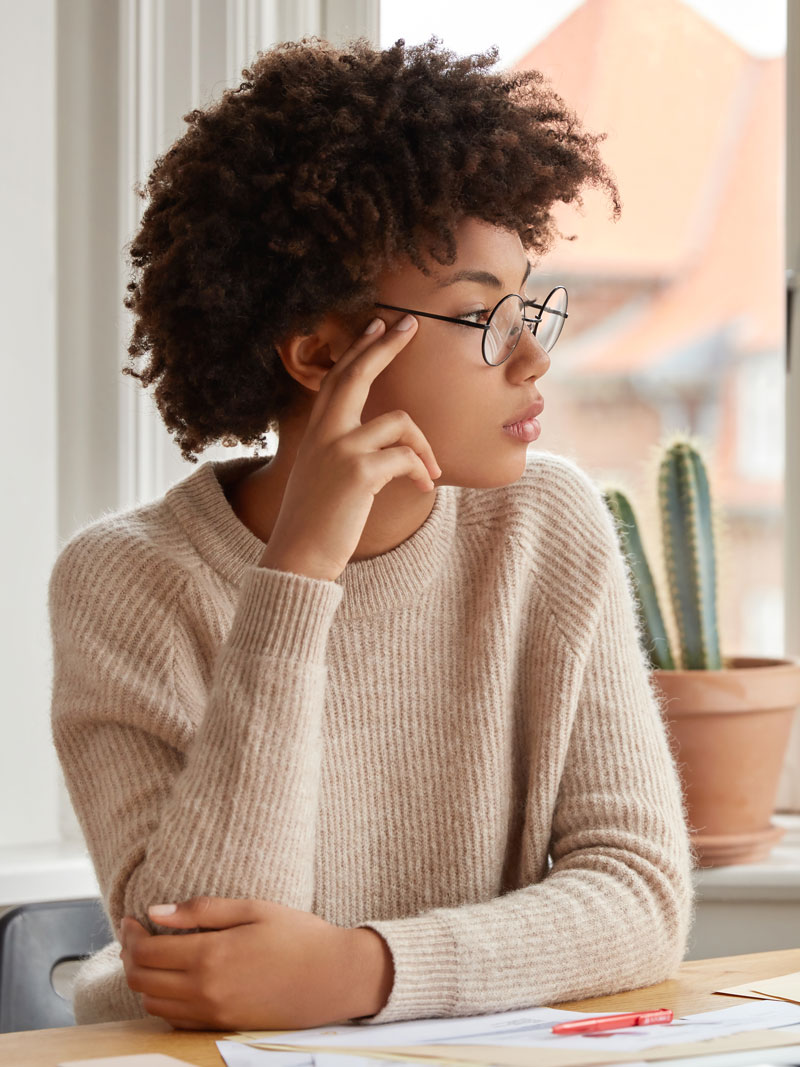 woman-with-oced african american woman sitting and staring out the window looking worried