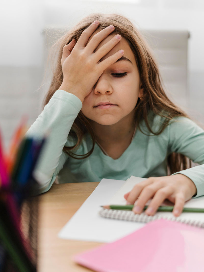 anxious girl sits next to her homework while she worries about school